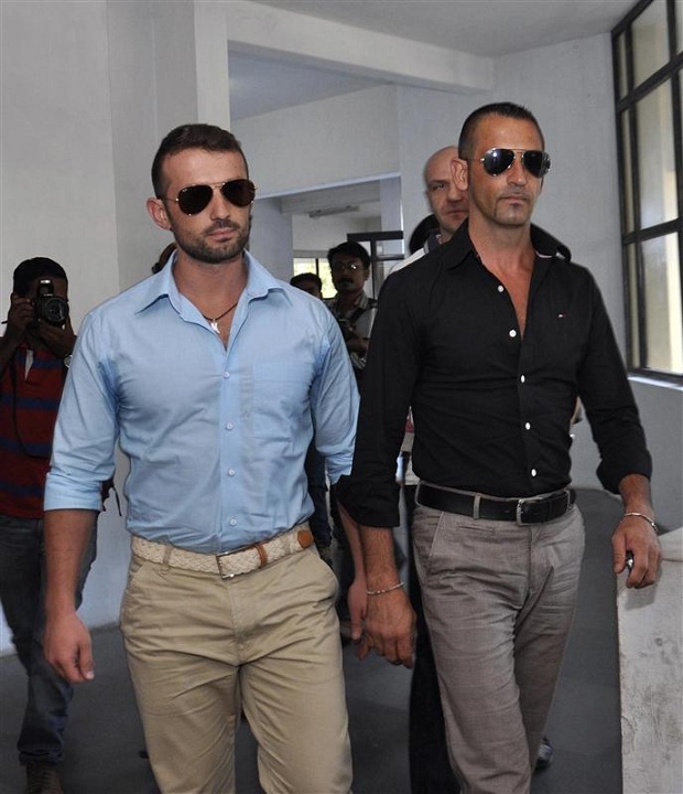 Italian sailors Latorre and Girone walk inside a police commissioner's office in Kochi